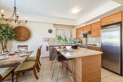a kitchen with wooden cabinets and a table with chairs at Villa Jacqueline in Protaras