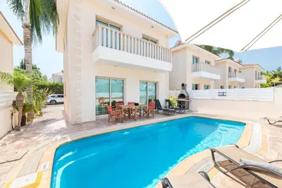 a villa with a swimming pool in front of a house at Villa Jacqueline in Protaras