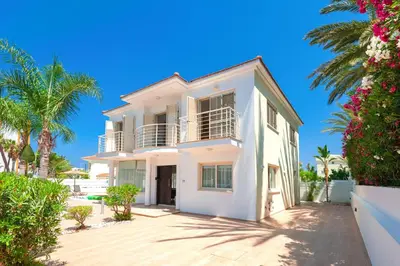 a white house with palm trees in front of it at Villa Anemona - 100m from Pernera Beach in Protaras