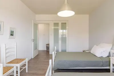 a white bedroom with a bed and a chair at Agia Napa three bedroom modern flat in Ayia Napa
