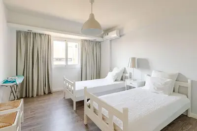 a white bedroom with two beds and a window at Agia Napa three bedroom modern flat in Ayia Napa