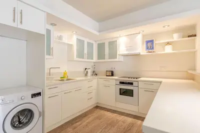 a kitchen with white cabinets and a washer and dryer at Agia Napa three bedroom modern flat in Ayia Napa