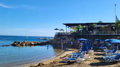 a beach with chairs and umbrellas and the ocean at Mythical Sands resort - Hana in Paralimni