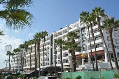 a large white building with palm trees in front of it at Les Palmiers Sunorama Beach Apartments in Larnaka