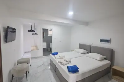 a white bedroom with a bed and a chair at Gold Emerging Villas Ltd Apart 5 in Ayia Napa