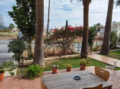 a wooden table sitting on a patio with palm trees at Lovely house apartment 2 bedrooms wiht nice view in Voroklini
