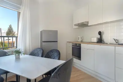 a white kitchen with a table and chairs and a window at Phaedrus Living City Breeze Residences Urbanity in Larnaka