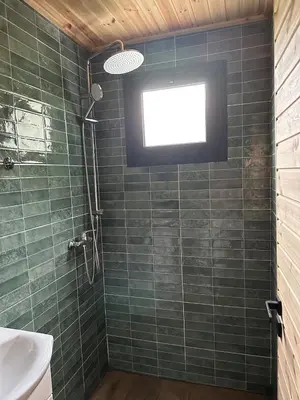 a bathroom with a shower with green tiles and a window at Warm Family Glamping Cabin with Kids Playground in Arakapas