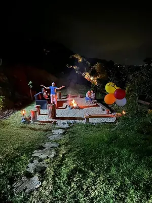 a group of people standing around a fire pit at night at Warm Family Glamping Cabin with Kids Playground in Arakapas