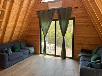 a living room with two couches and large windows at Warm Family Glamping Cabin with Kids Playground in Arakapas