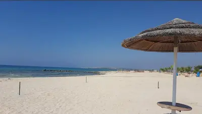 a straw umbrella sitting on a beach next to the ocean at Ayia Napa Villa Jasmine Sirens Beach Dom na Cyprze in Ayia Napa