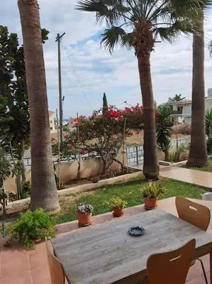 a wooden table with chairs and palm trees at Lovely house apartment Oroklini in Voroklini