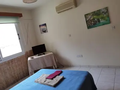 a room with a bed with a table and a window at Lovely house apartment Oroklini in Voroklini