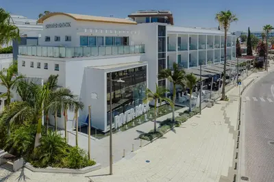 a large white building on a street with palm trees at River Rock Hotel in Ayia Napa