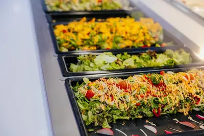 a row of trays filled with different types of food at River Rock Hotel in Ayia Napa