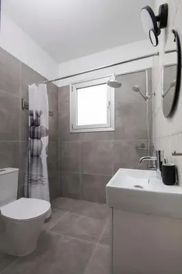 a bathroom with a toilet and a sink and a window at Amazing Two Bedroom Apartment in Larnaka