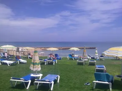 a group of lawn chairs and umbrellas on a beach at Maison Diana - Tourism license 6990 in Protaras