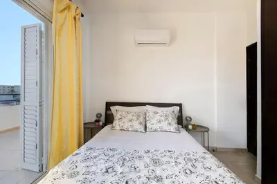 a bedroom with a bed and a yellow curtain at City Center Top Floor Big Balcony 2BR Close to the Beach in Larnaka