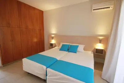 a bedroom with a large bed with blue pillows at Sea CleoNapa Hotel in Ayia Napa