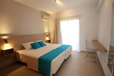 a bedroom with a bed with blue pillows and a window at Sea CleoNapa Hotel in Ayia Napa