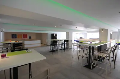 a room with tables and chairs and a kitchen at Sea CleoNapa Hotel in Ayia Napa