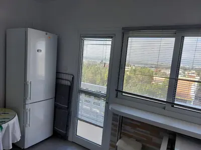 a kitchen with a refrigerator and two large windows at ideal famille panoramic view lac salé in Larnaka