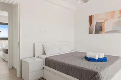 a white bedroom with a bed with a blue towel on it at Serenity Waves Villa 19 in Larnaka