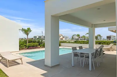 a patio with a table and chairs next to a swimming pool at Serenity Waves Villa 19 in Larnaka