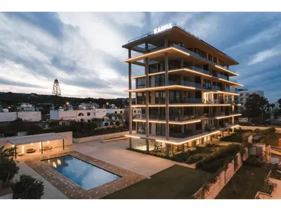 a tall building with a swimming pool in front of it at Protaras Eden Seaside Suite in Protaras