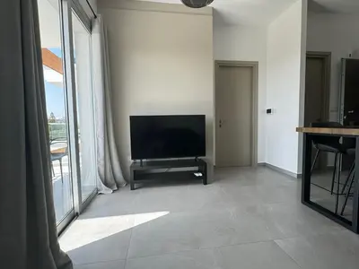 a living room with a flat screen tv and a table at Limassol Beautiful Apartment in Limassol