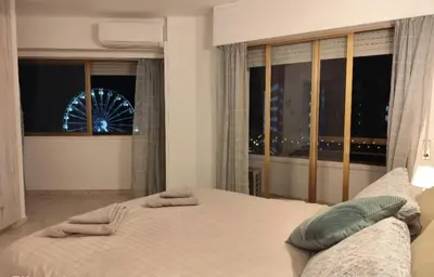 a bedroom with a bed and a window with a ferris wheel at Marina view seaside apartment in Larnaka