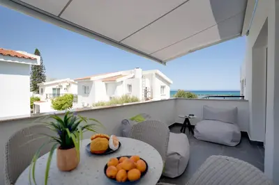 a patio with a table and chairs on a balcony at Sea Front Luxury Apartment in Voroklini