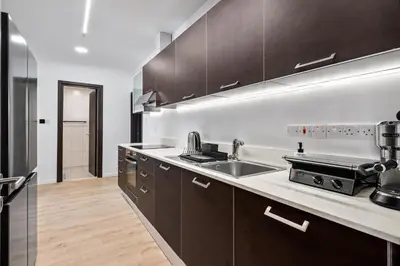 a kitchen with brown cabinets and a sink and a counter at Paradise Apartment with Private Pool & Sea View in Larnaka