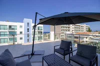 a patio with two chairs and an umbrella at Beachside 1-bed with huge veranda in Protaras