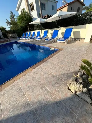 a swimming pool with blue lounge chairs next to a house at Ayia Napa Marina Luxury Villas - Diamond in Ayia Napa