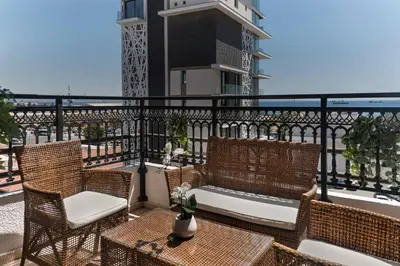 a balcony with wicker chairs and tables on a building at Phaedrus Living Seaview Phinikoudes Flat in Larnaka