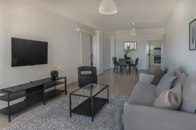 a living room with a couch and a tv on a wall at Phaedrus Living Seaview Phinikoudes Flat in Larnaka