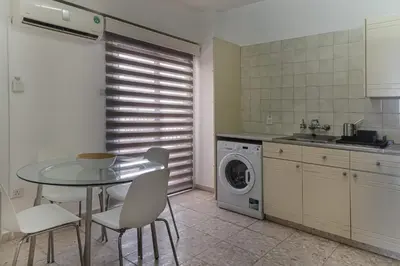 a kitchen with a table and a washing machine at Phaedrus Living Seaview Phinikoudes Flat in Larnaka