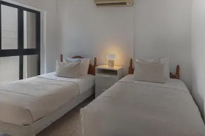 two beds in a white room with a window at Phaedrus Living Seaview Phinikoudes Flat in Larnaka