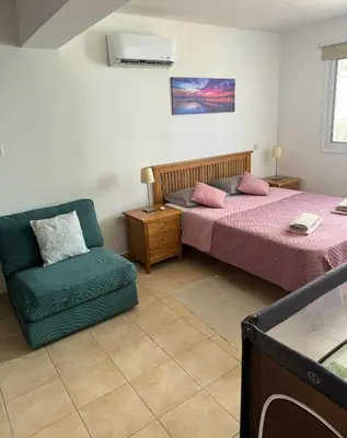 a bedroom with two beds and a chair at Apartment Veronika in Paralimni