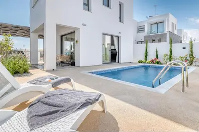 a white house with a swimming pool in a yard at Luxurious Villa Alasia in Paralimni in Paralimni
