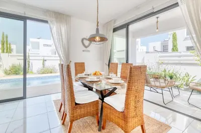 a dining room with a table and wicker chairs at Luxurious Villa Alasia in Paralimni in Paralimni
