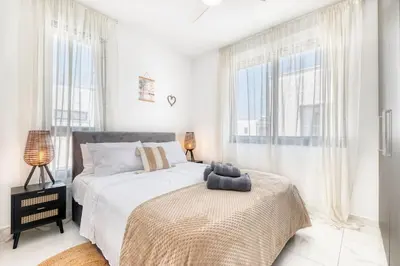 a white bedroom with a bed and two windows at Luxurious Villa Alasia in Paralimni in Paralimni