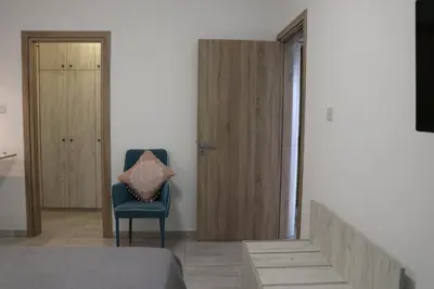 a bedroom with a blue chair with a pillow on it at Layiotis Hotel in Larnaka