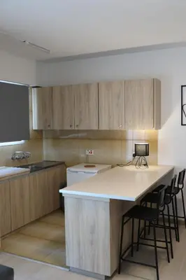a kitchen with wooden cabinets and a counter with bar stools at Layiotis Hotel in Larnaka