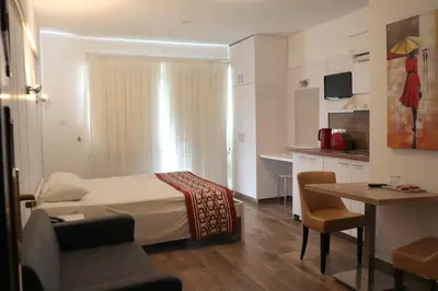 a bedroom with a bed and a table and a kitchen at Layiotis Hotel in Larnaka