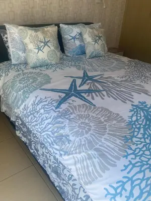 a bed with a blue and white blanket and pillows at Luxary Vacation by the Sea Protaras in Protaras