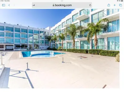 a view of a building with a swimming pool and palm trees at Luxary Vacation by the Sea Protaras in Protaras