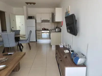 a kitchen and living room with a table and a tv at Luxary Vacation by the Sea Protaras in Protaras
