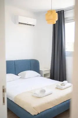 a bedroom with a bed with a blue headboard and a window at Hubstay Tamara Gardens 2 Bed Apt Suite with Pool in Livadhia